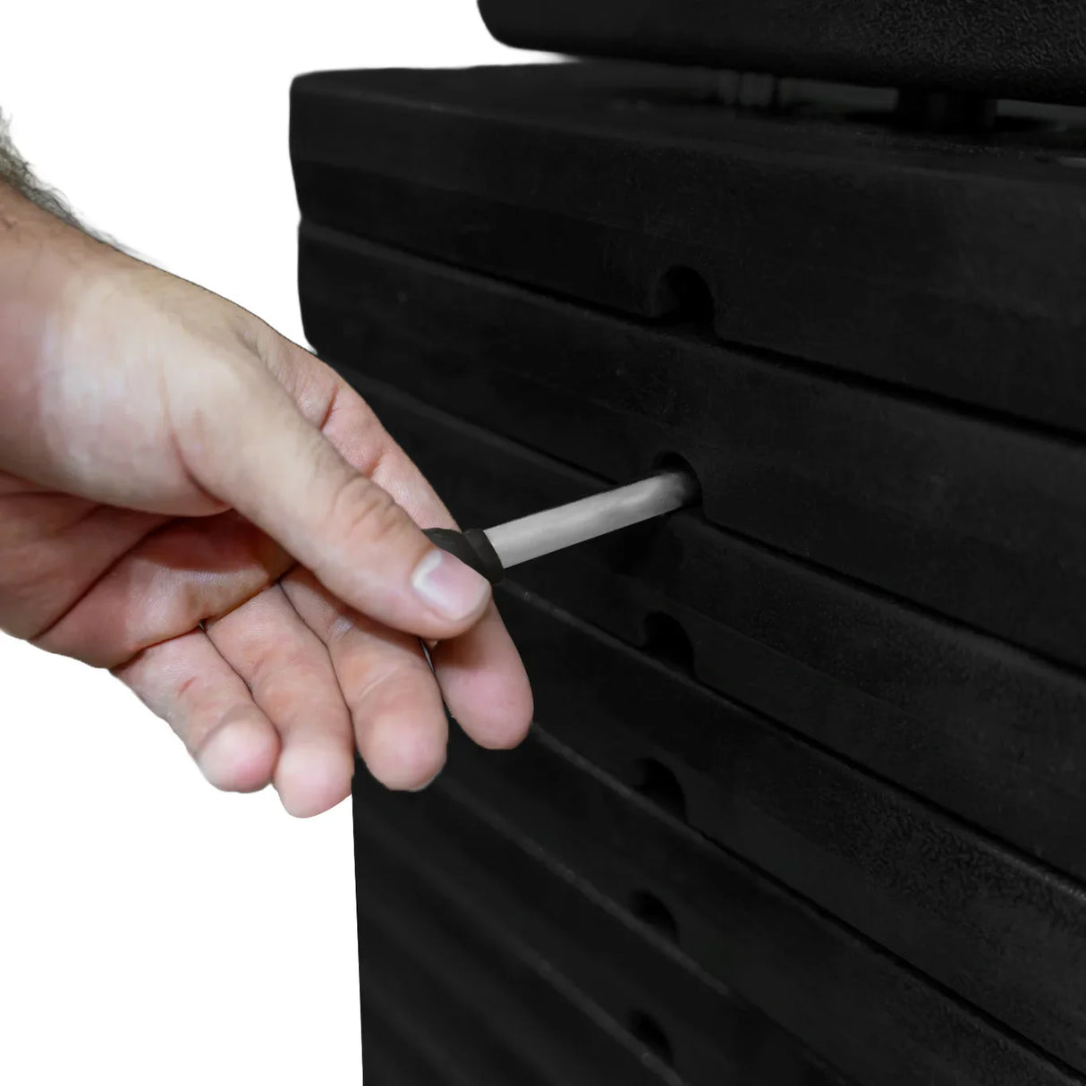 Hand adjusting the weight pin on a stack of black weight plates for a wall-mounted cable pulley machine