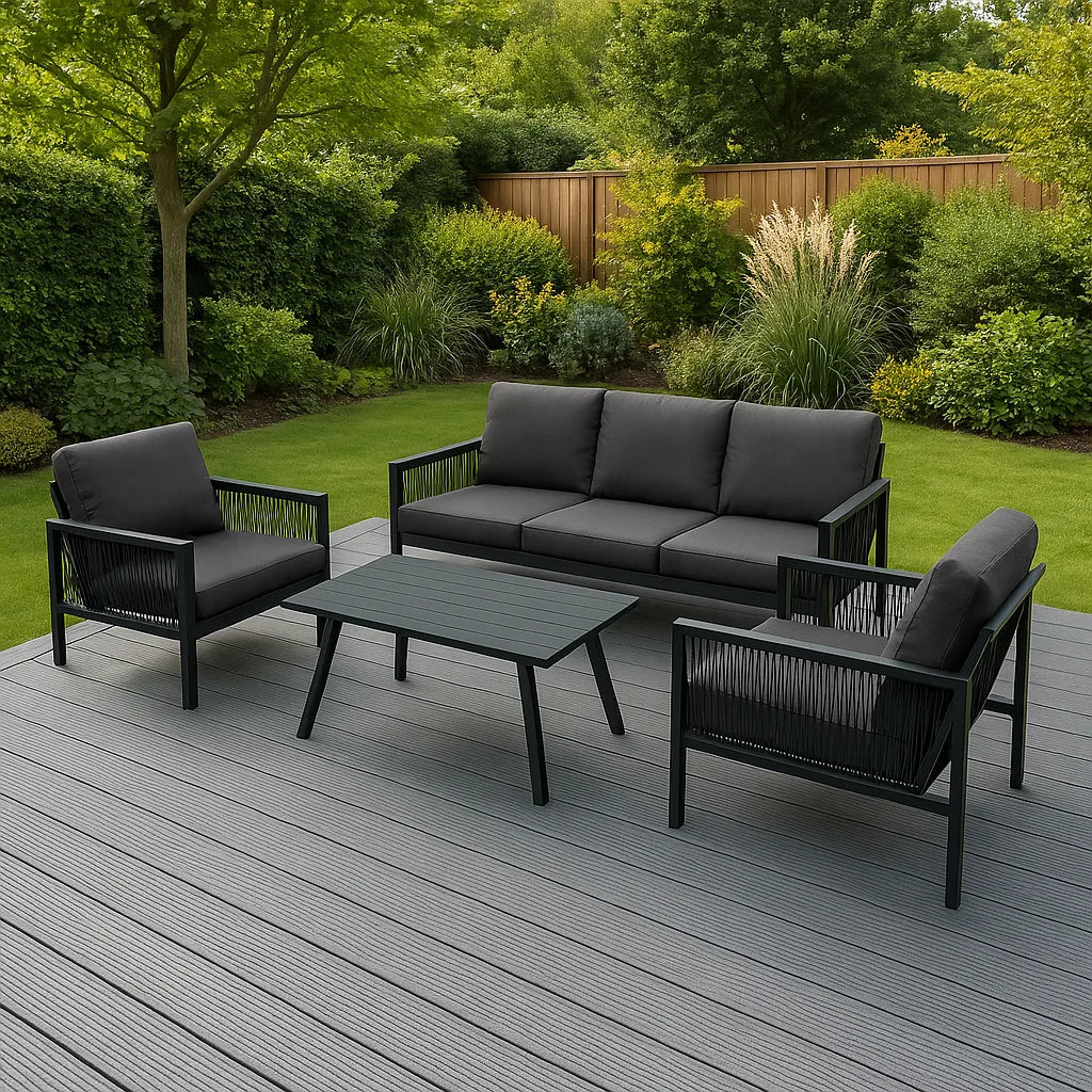 Grey composite decking boards arranged in a modern outdoor setting with black furniture and lush green landscaping