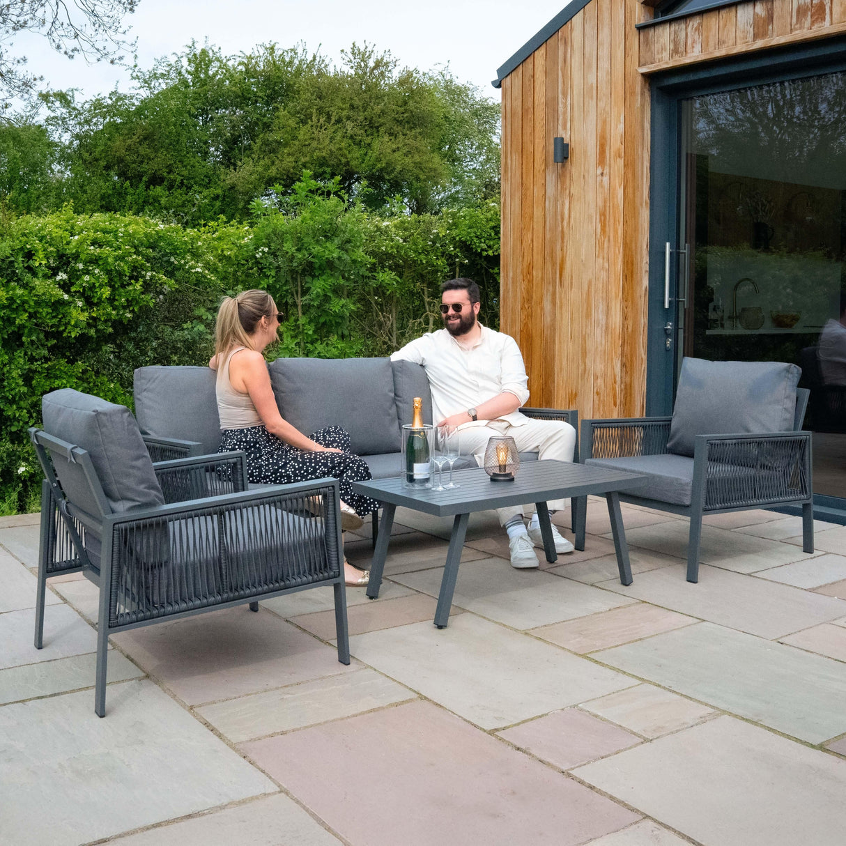 Anthracite grey aluminium 4-piece sofa set with comfortable cushions, paired with a black rattan storage box, perfect for outdoor relaxation