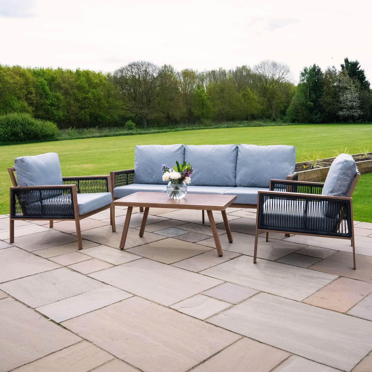 Aluminium 4 piece sofa set featuring grey cushions, wood effect table, and black rattan storage box, perfect for outdoor lounging
