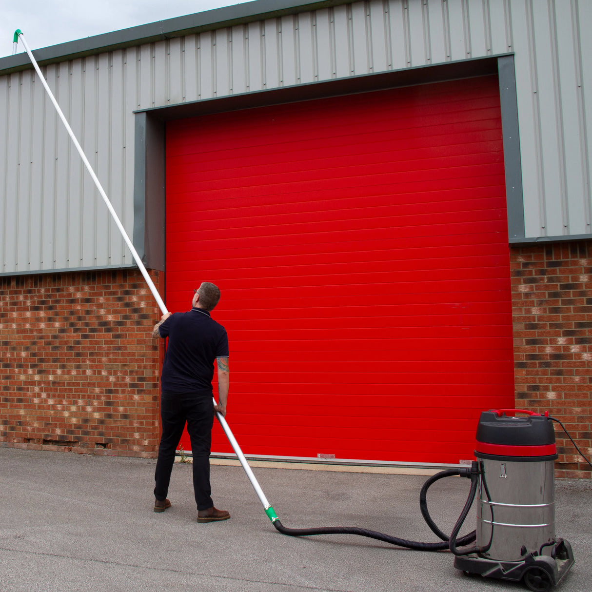 80L wet and dry vacuum with gutter vacuum poles and 5m hose, shown in use against a red garage door, highlighting its versatility