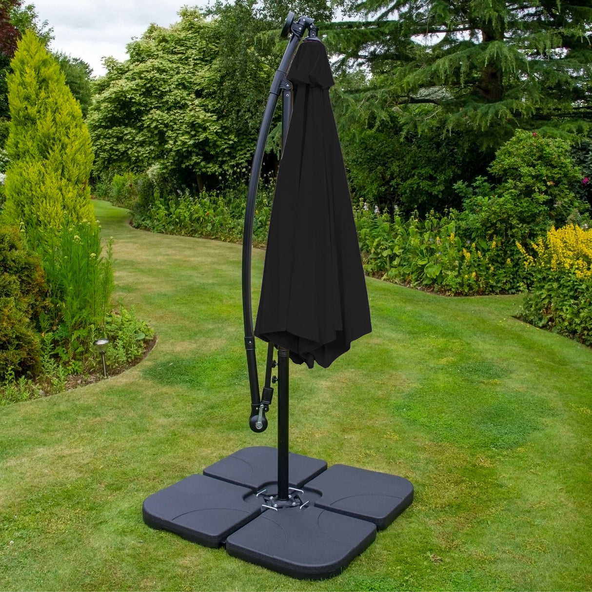 Anthracite 4 piece sofa set with a sleek black parasol and sturdy base, set in a lush garden with vibrant greenery and soft grass