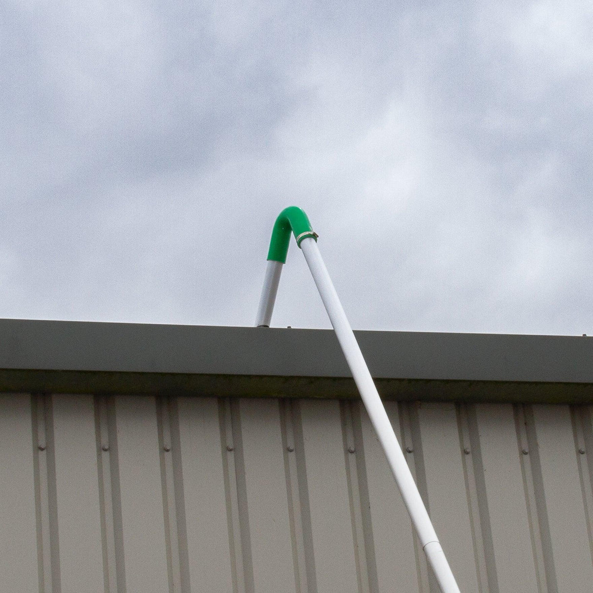 Gutter vacuum poles with a green connector extending over a building's edge, designed for efficient wet and dry vacuuming