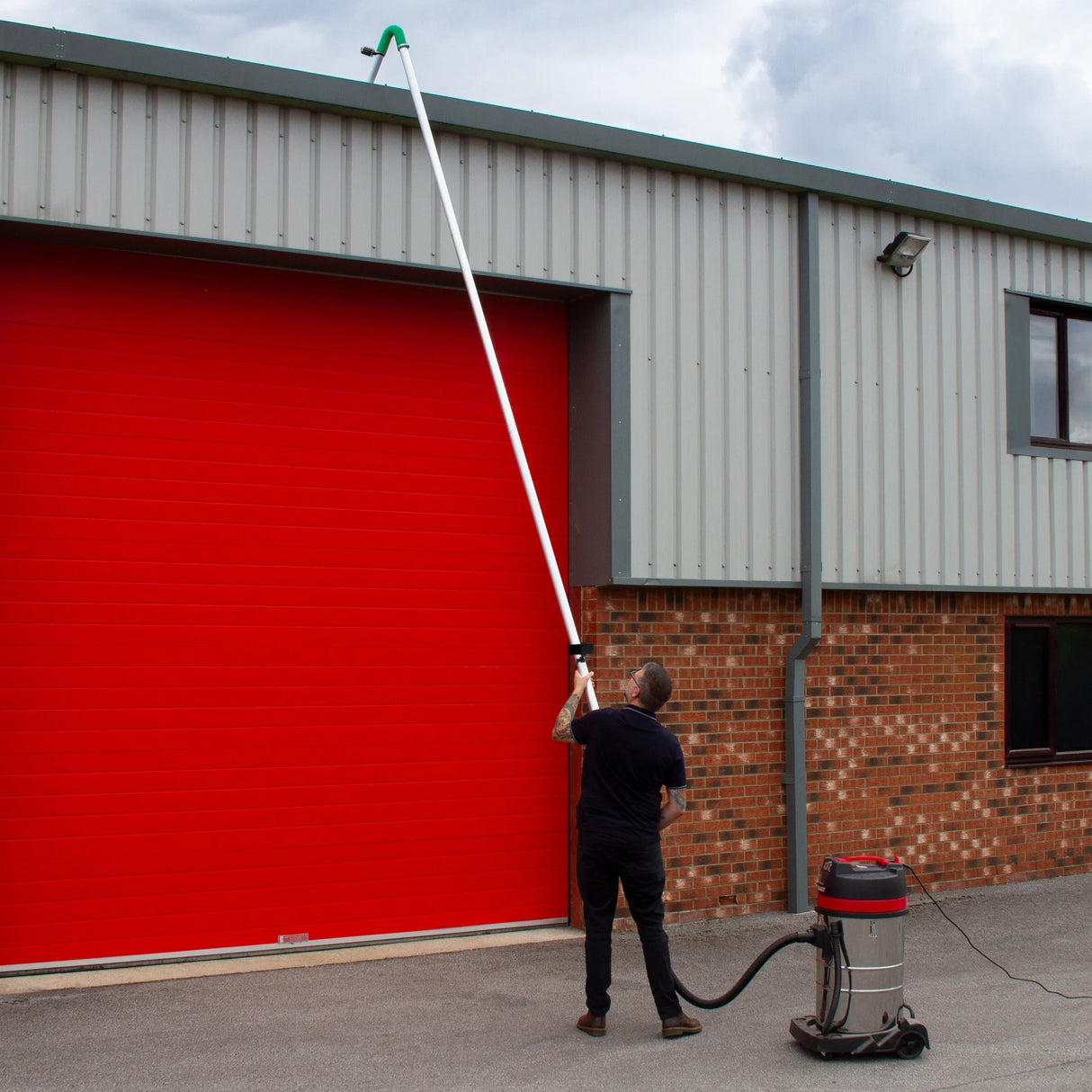 80L wet and dry vacuum with gutter vacuum poles, user extending pole towards a red garage door, showcasing versatility and reach