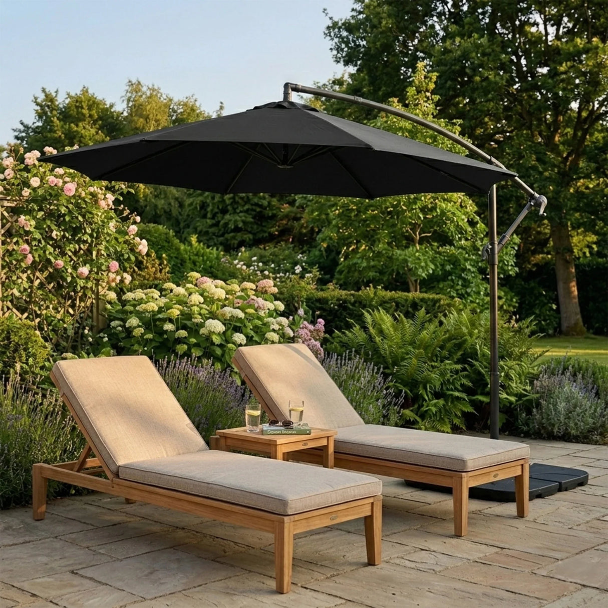 Stylish black cantilever parasol providing shade over two beige lounge chairs and a small wooden table in a lush garden setting