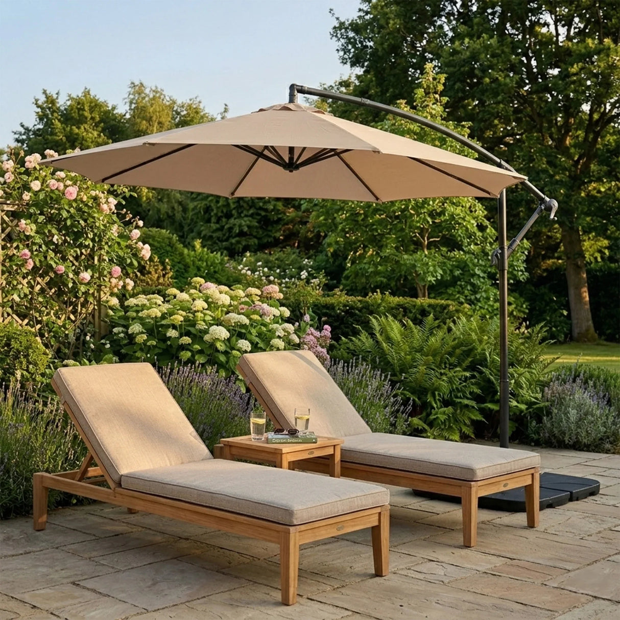 Beige cantilever parasol providing shade over two wooden lounge chairs beside a small table in a lush garden setting