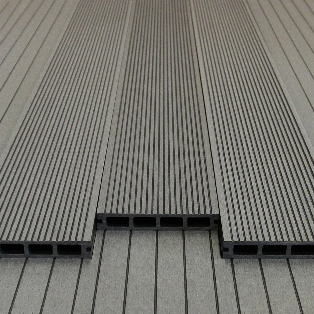 Castle Grey composite decking boards with a textured surface and hollow design, arranged neatly in a linear pattern