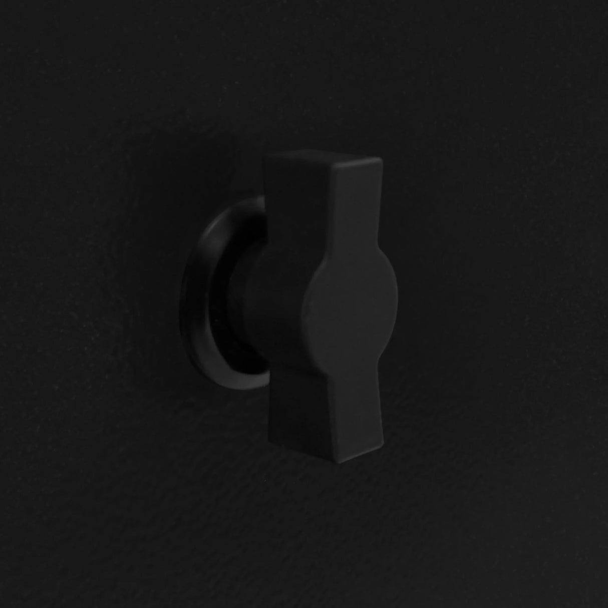 Black locking mechanism on a textured surface, designed for securing a 6kg gas bottle locker, featuring a sturdy, compact shape