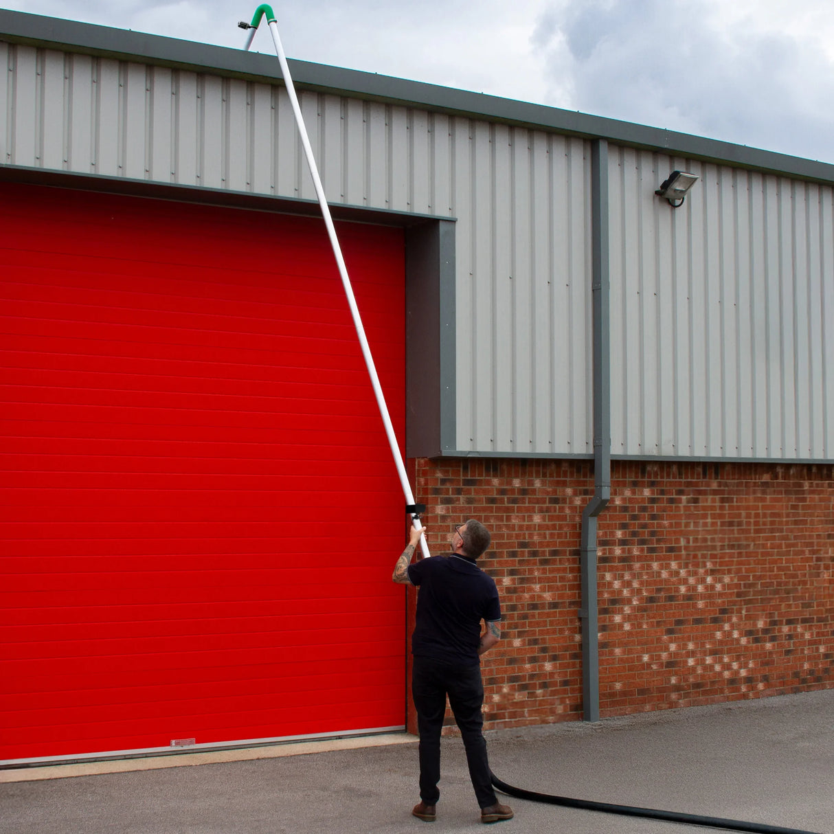 50L wet and dry vacuum with extended gutter vacuum pole, user reaching high to clean gutters near a red garage door