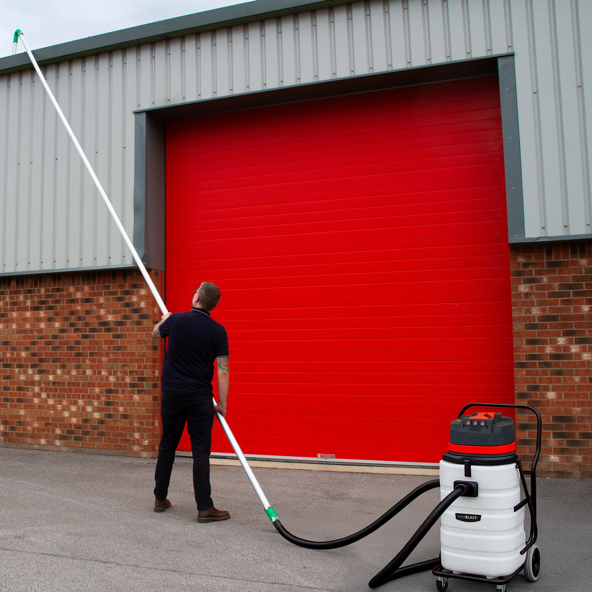 90L wet and dry vacuum with gutter vacuum poles and 5m hose, featuring a sturdy design and a user aiming at a red garage door