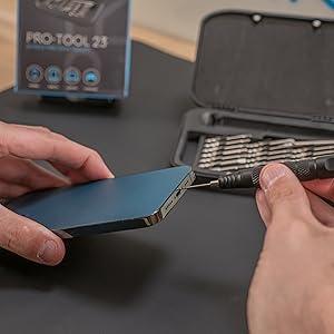 Precision screwdriver set in use, featuring a sleek black handle and various interchangeable bits, repairing a smartphone on a work surface