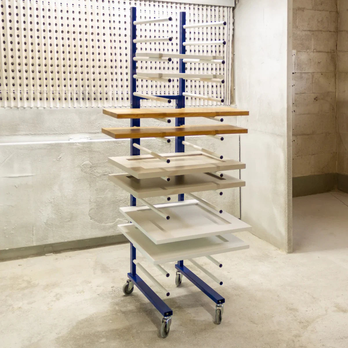Monster Racking Spray Drying Rack Trolley with five adjustable shelves in natural wood and white finishes, mounted on a blue metal frame