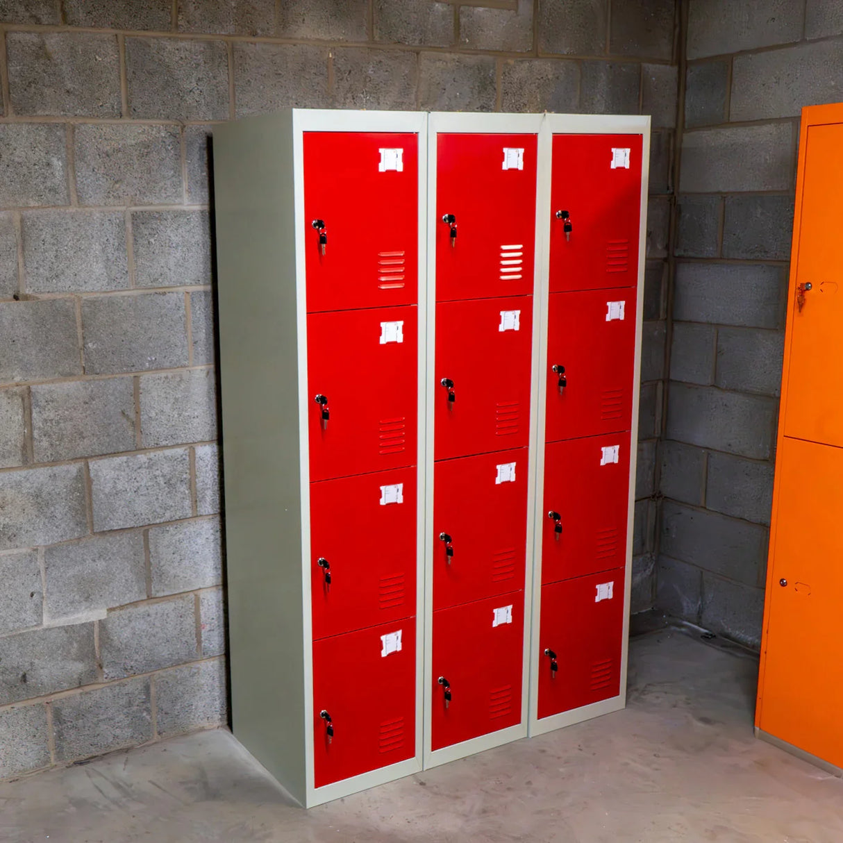 Four-door metal storage lockers in vibrant red, featuring ventilation slots and secure locks, arranged in a compact, organized layout