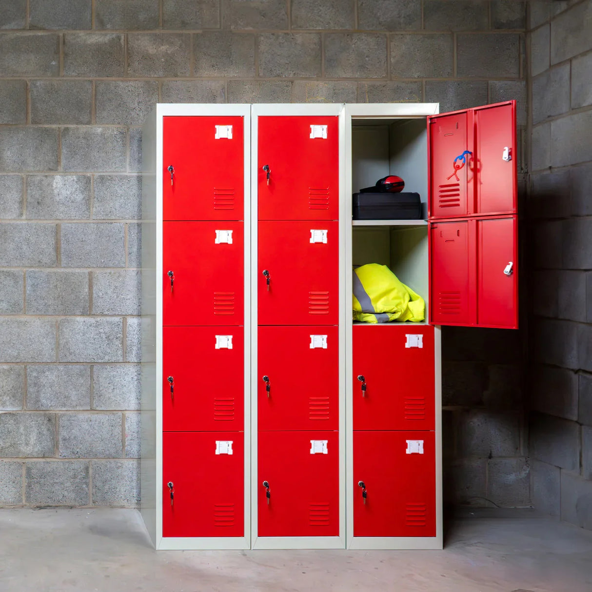 Four-door metal storage lockers in vibrant red, featuring a smooth finish, with one door open revealing yellow and black items inside