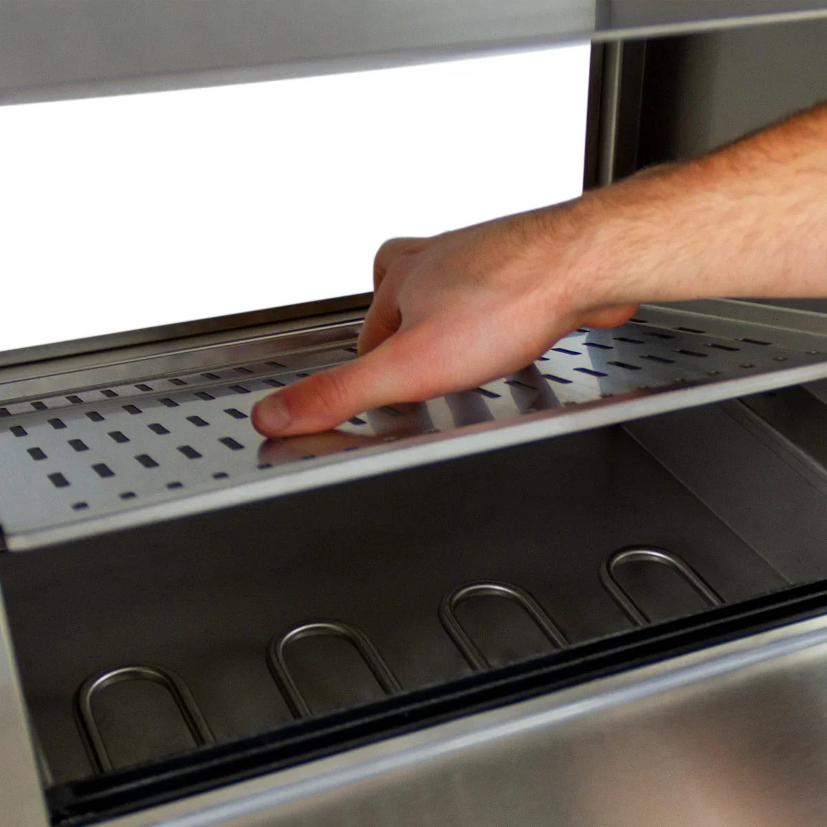 Stainless steel hot dog steamer cart with a hand adjusting the perforated tray, showcasing its spacious interior and sleek design