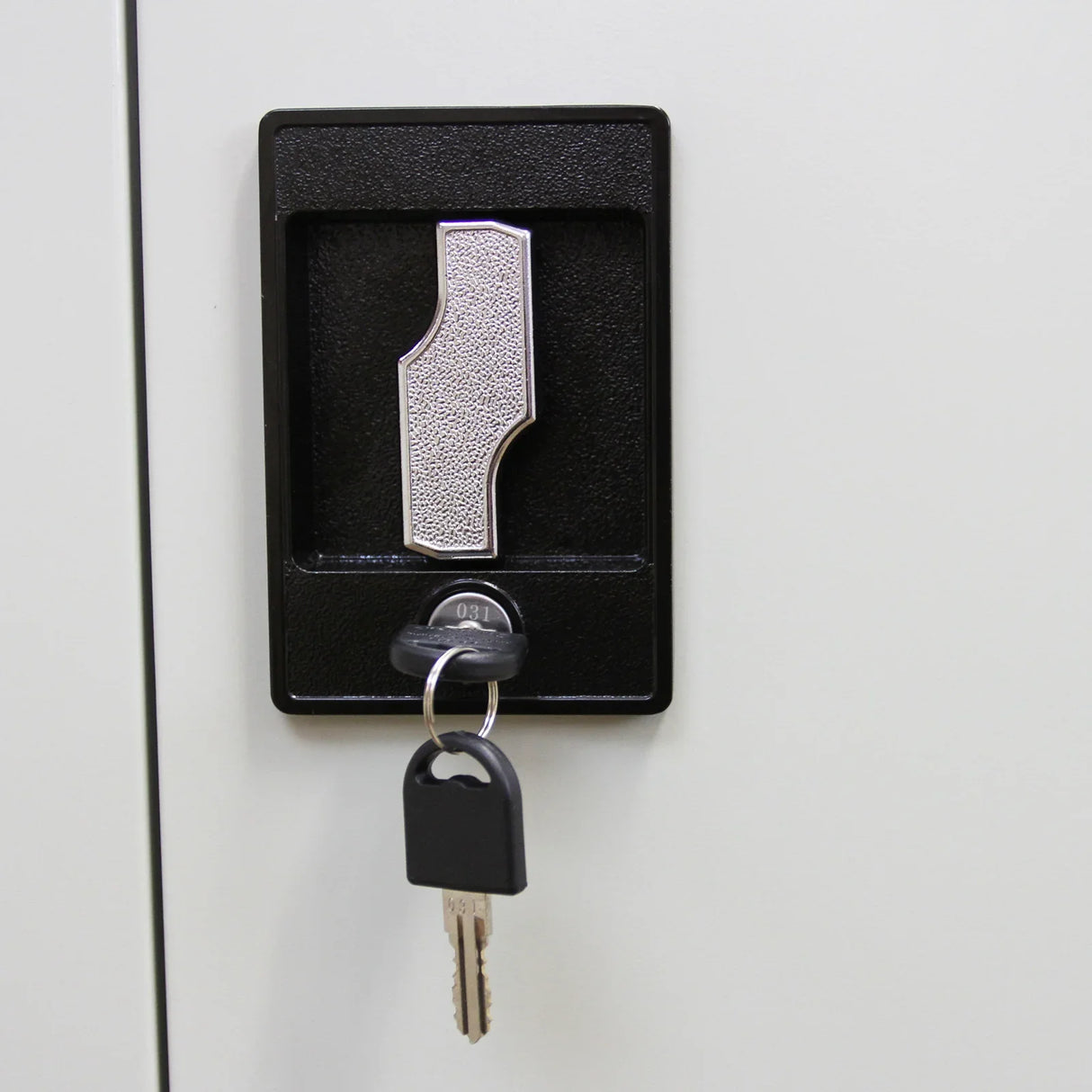 Close-up of a metal filing cabinet lock with a textured silver keyhole and a key inserted, showcasing security features and durability