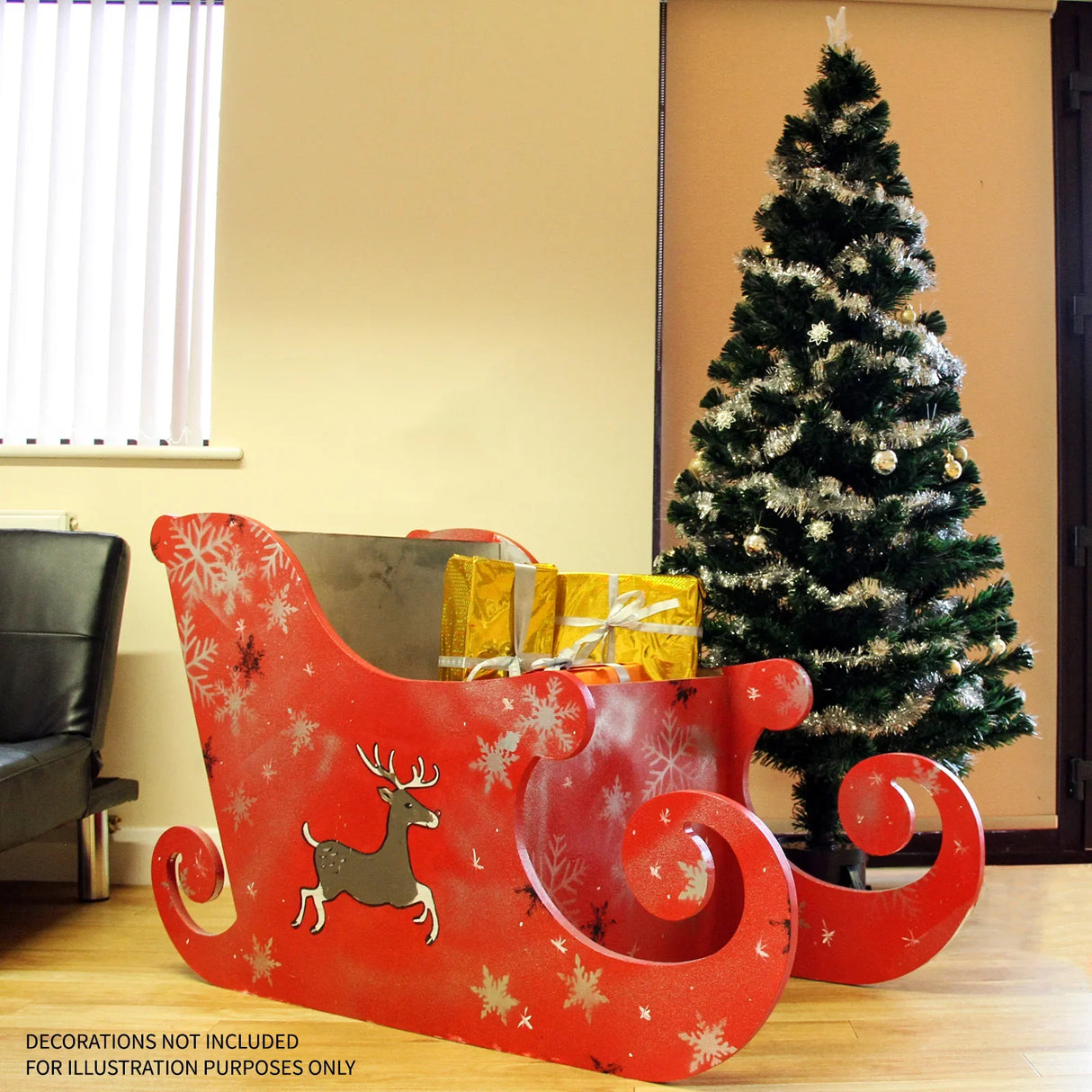 Vibrant red MDF Santa sleigh with decorative reindeer and snowflakes, set beside a festive Christmas tree, perfect for holiday decor