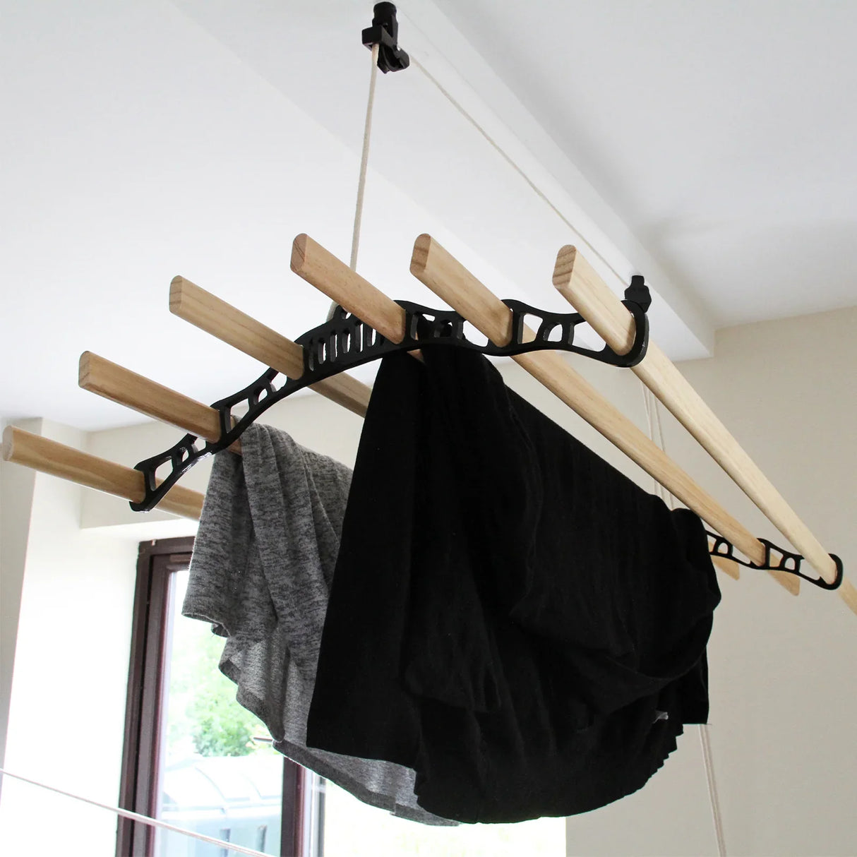 Ceiling pulley clothing airer in black with wooden drying rods, showcasing black and gray garments hanging for drying indoors