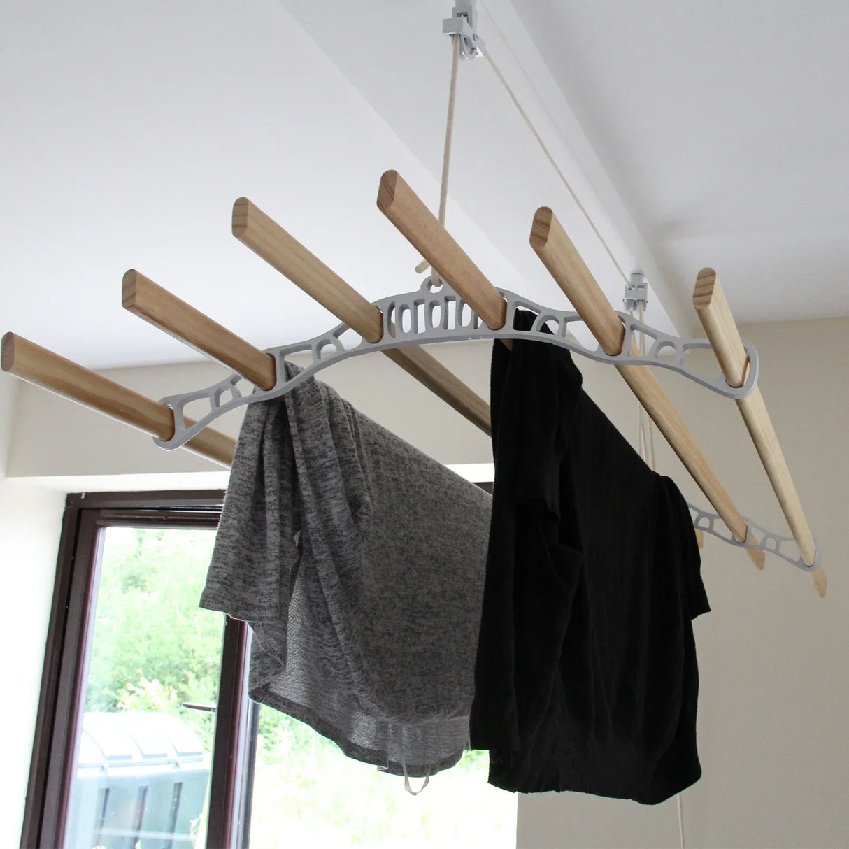 Ceiling pulley clothing airer in white with wooden rods, showcasing gray and black shirts hanging for efficient drying