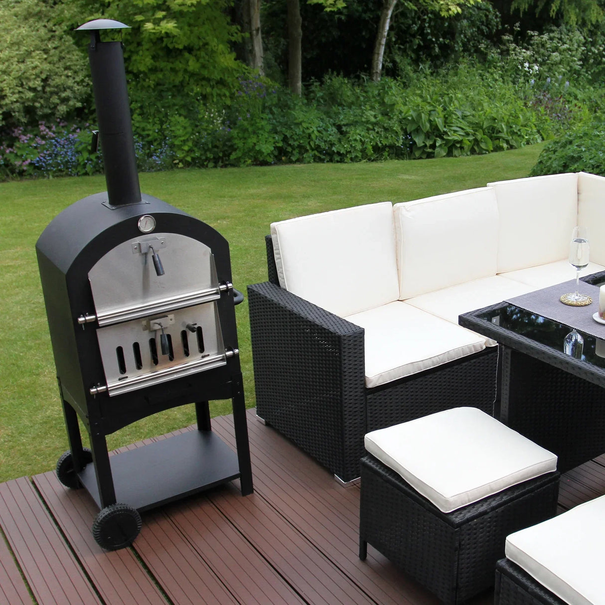 KuKoo outdoor pizza oven in sleek black with stainless steel accents, positioned next to a modern patio seating area on wooden decking