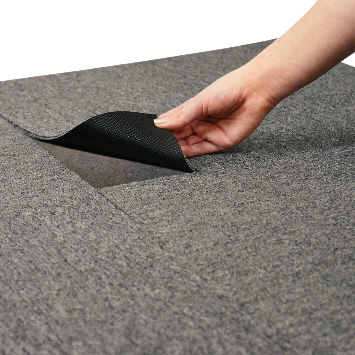 Anthracite carpet tile being lifted, showcasing its textured surface and durable backing, ideal for versatile flooring solutions