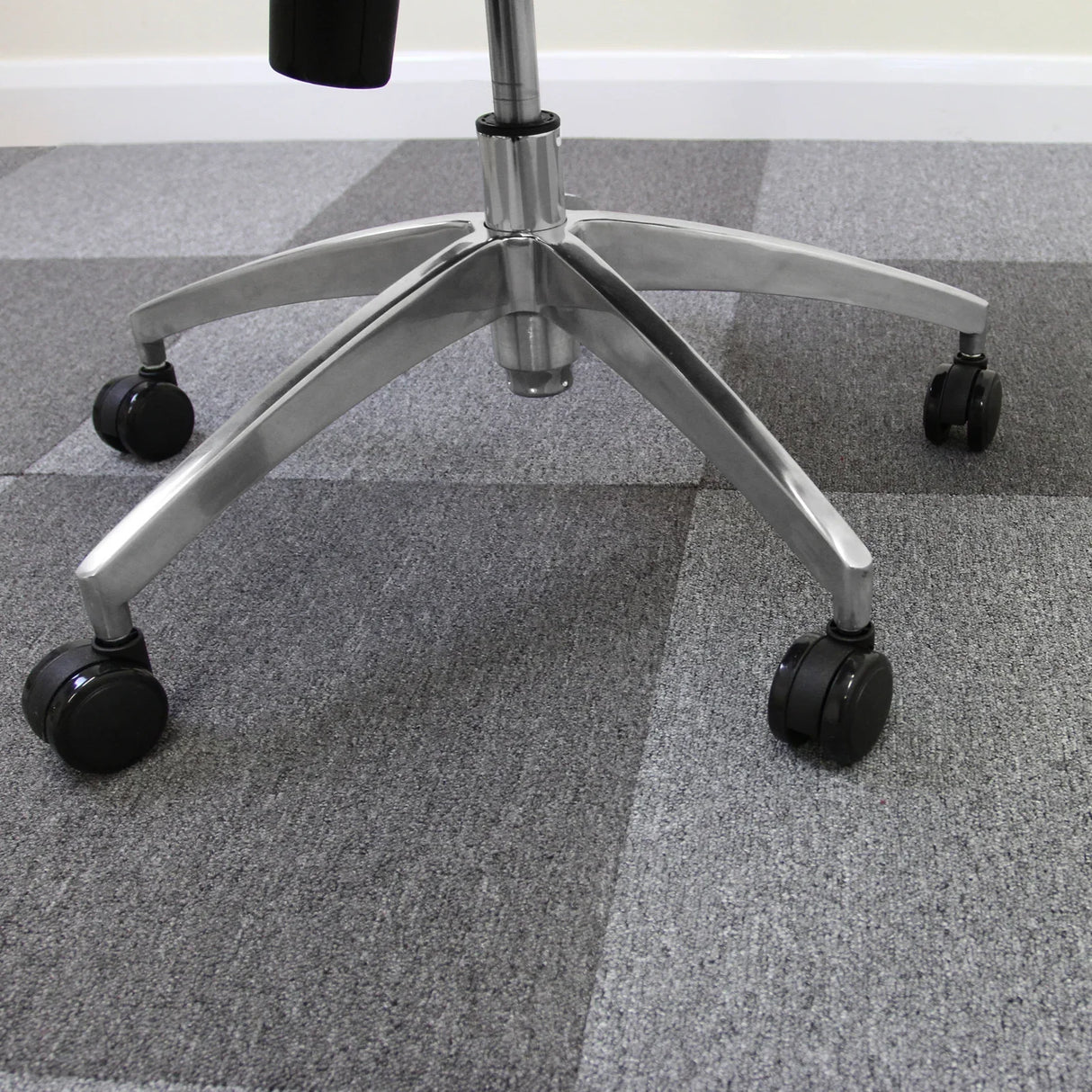 Platinum grey carpet tiles arranged in a square pattern, showcasing a soft texture under a swivel office chair with rolling wheels