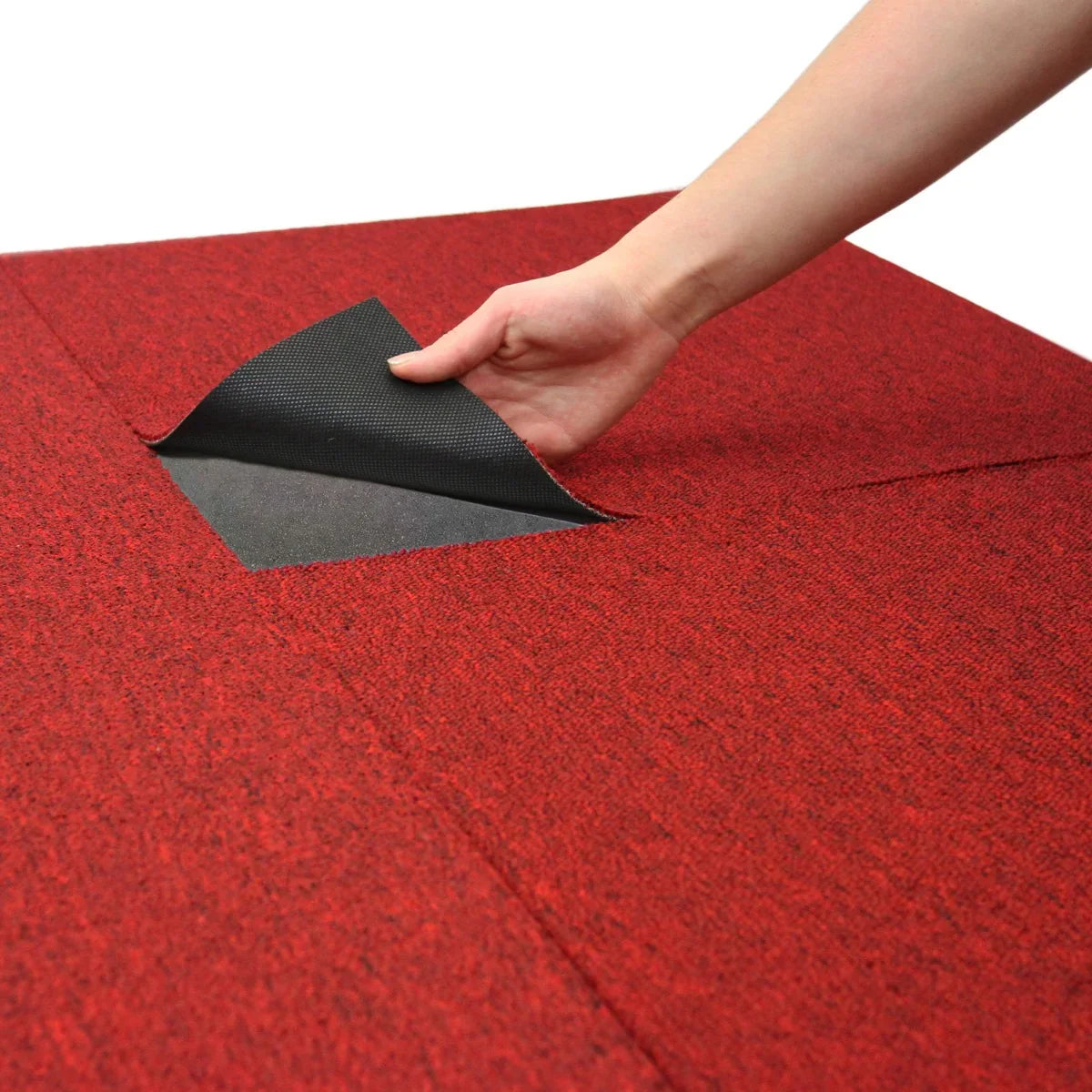 Scarlet red carpet tile being lifted, showcasing its textured surface and durable backing, ideal for stylish flooring solutions