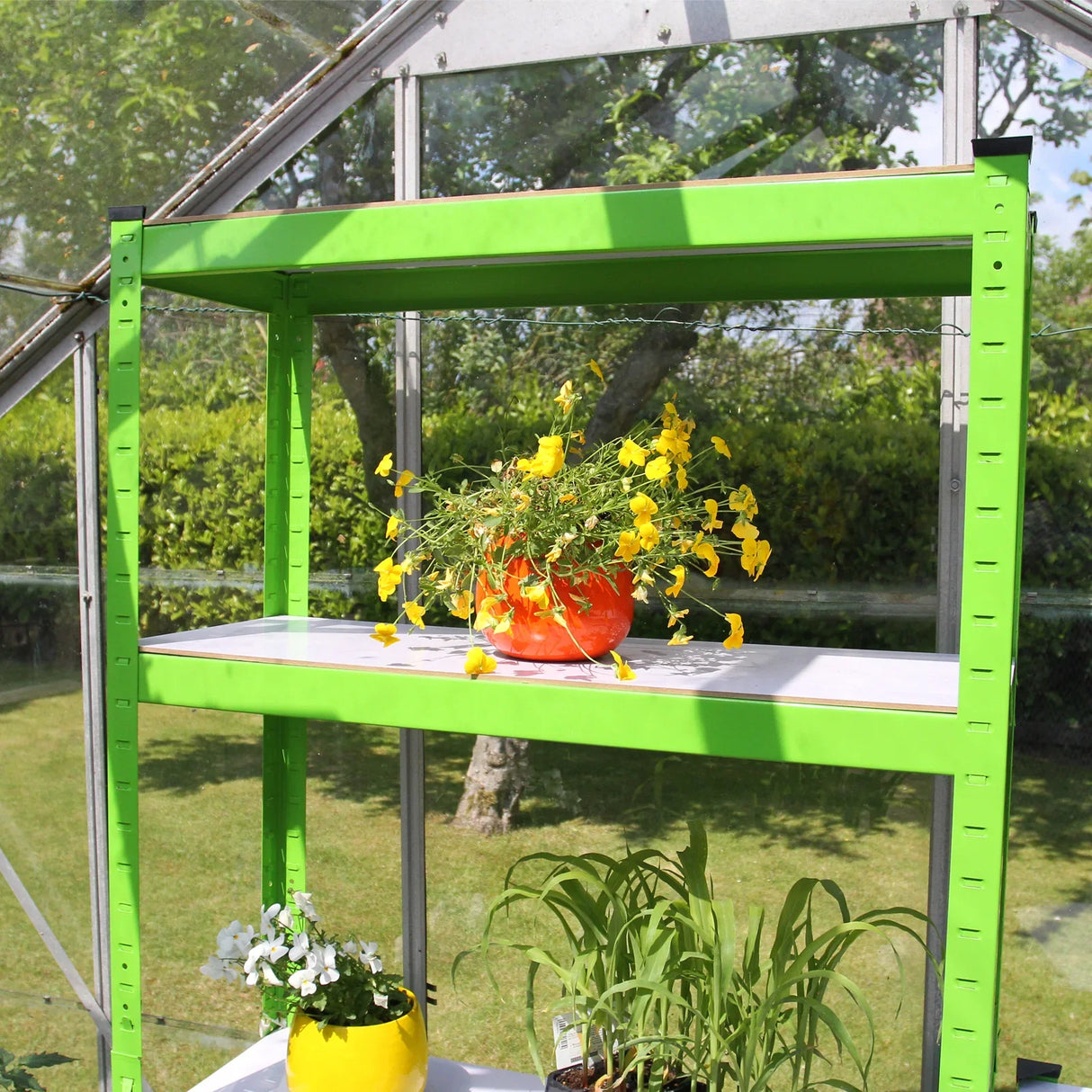 Bright green water-resistant racking with two shelves, showcasing vibrant flowers in pots, set inside a greenhouse with natural light