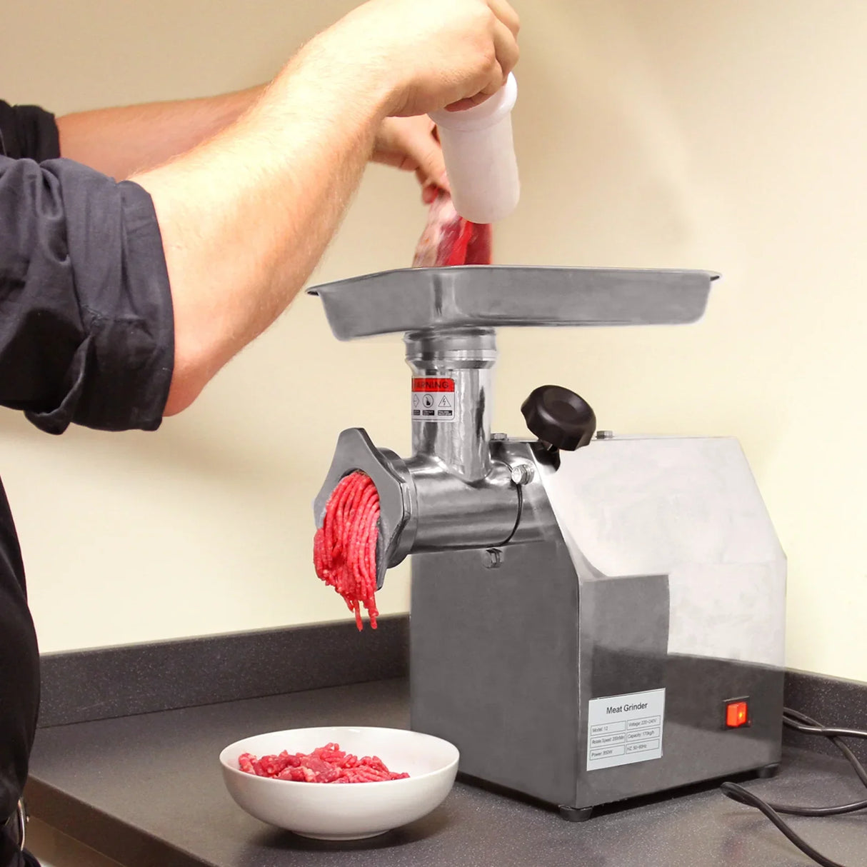 Stainless steel KuKoo Commercial Meat Grinder with ground meat being processed, featuring a sturdy design and easy-to-use hopper