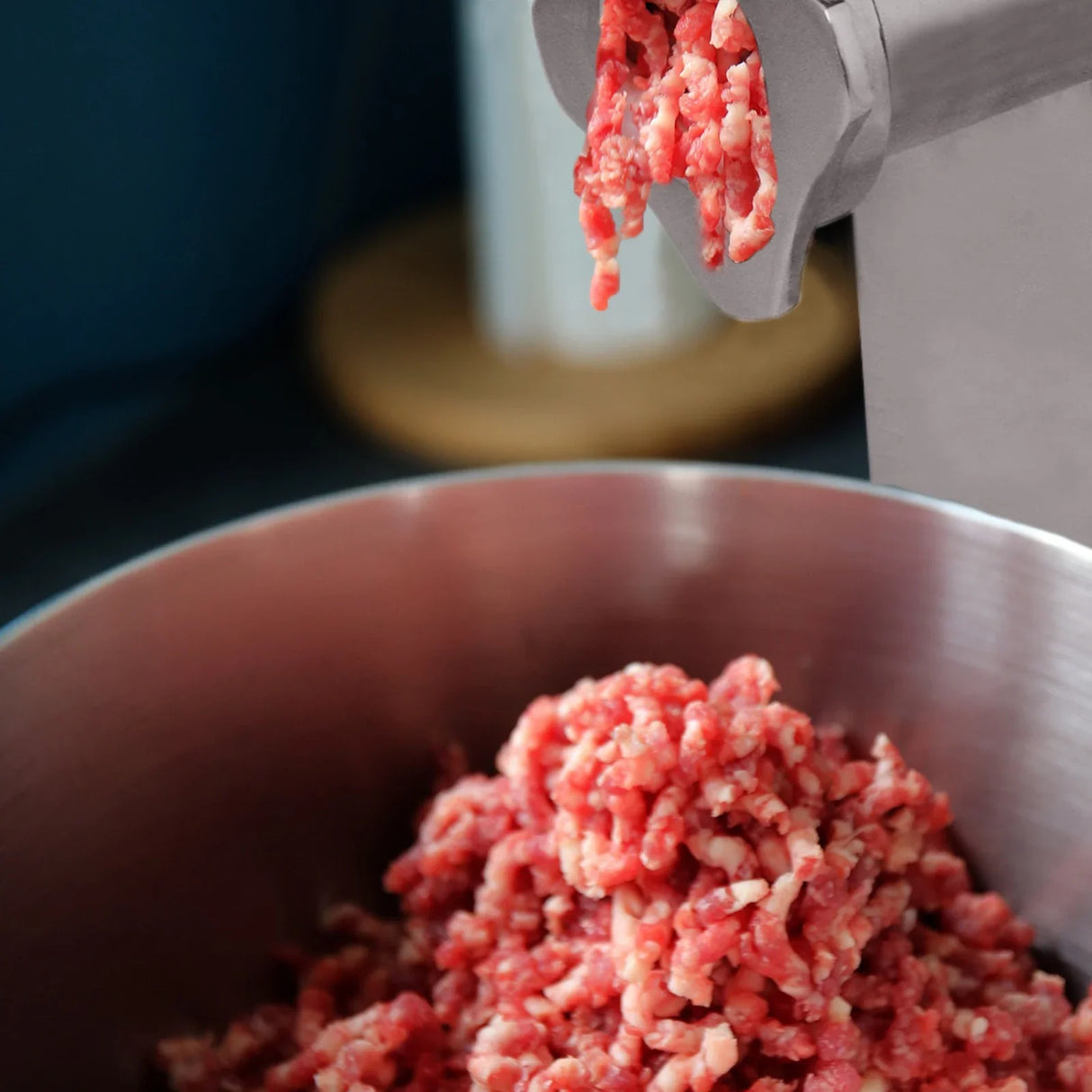 KuKoo Commercial Meat Grinder with freshly ground red meat falling into a stainless steel bowl, showcasing its efficient design and powerful performance