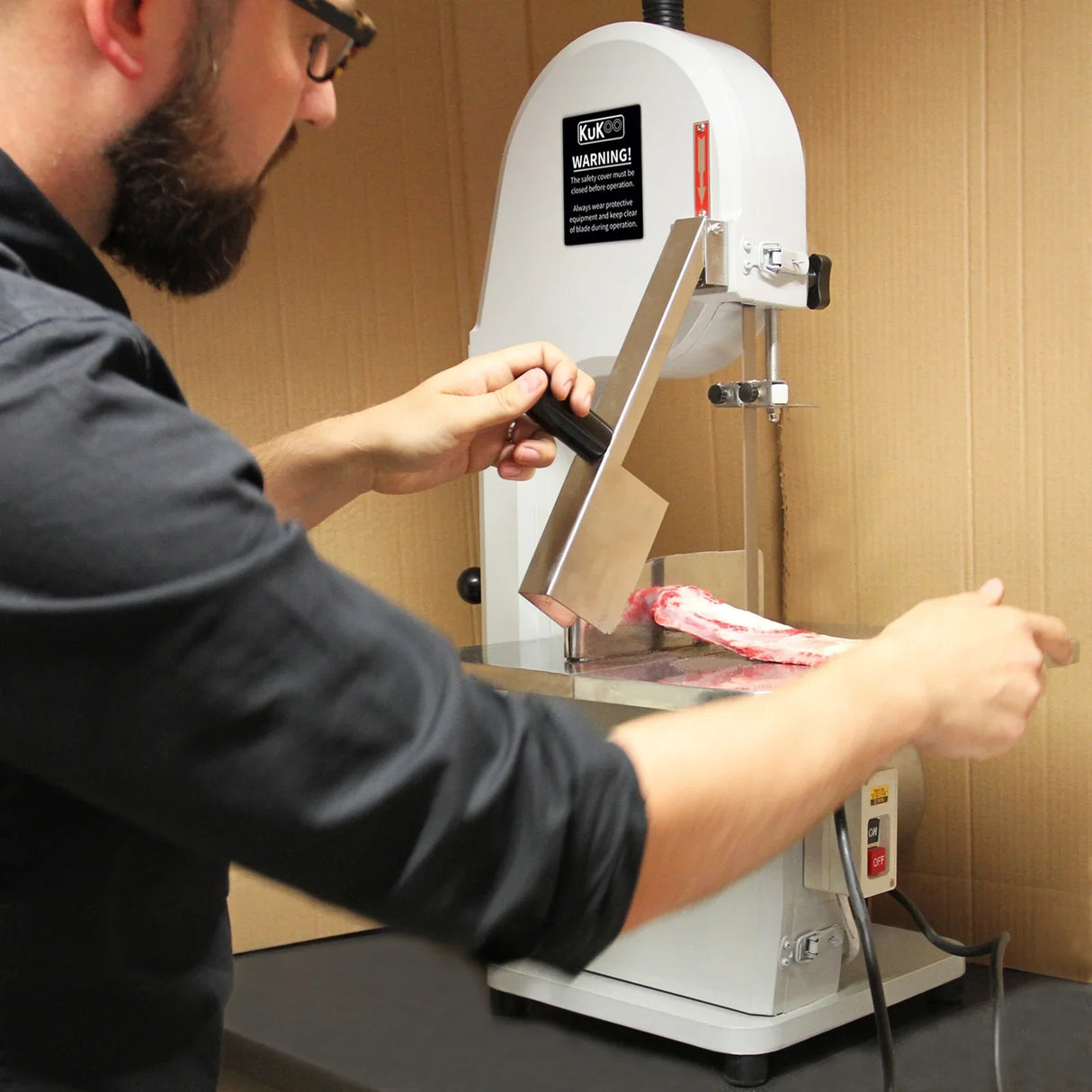 Kukoo Commercial Bone Saw Bandsaw in use, featuring a stainless steel blade, sturdy design, and a user cutting through meat with precision