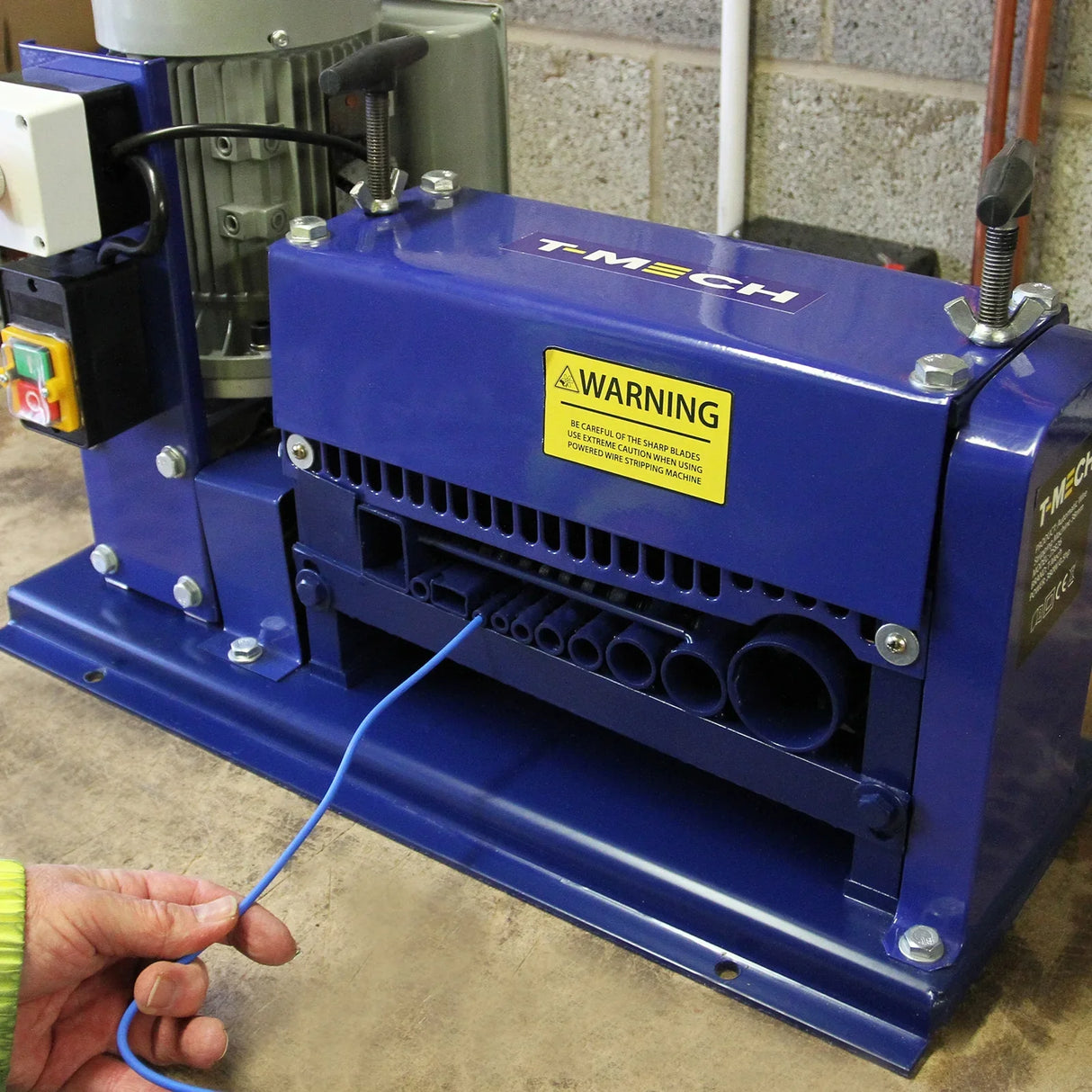 T-Mech Automatic Wire Stripper in blue, featuring a warning label, with a blue wire being fed into the machine for stripping