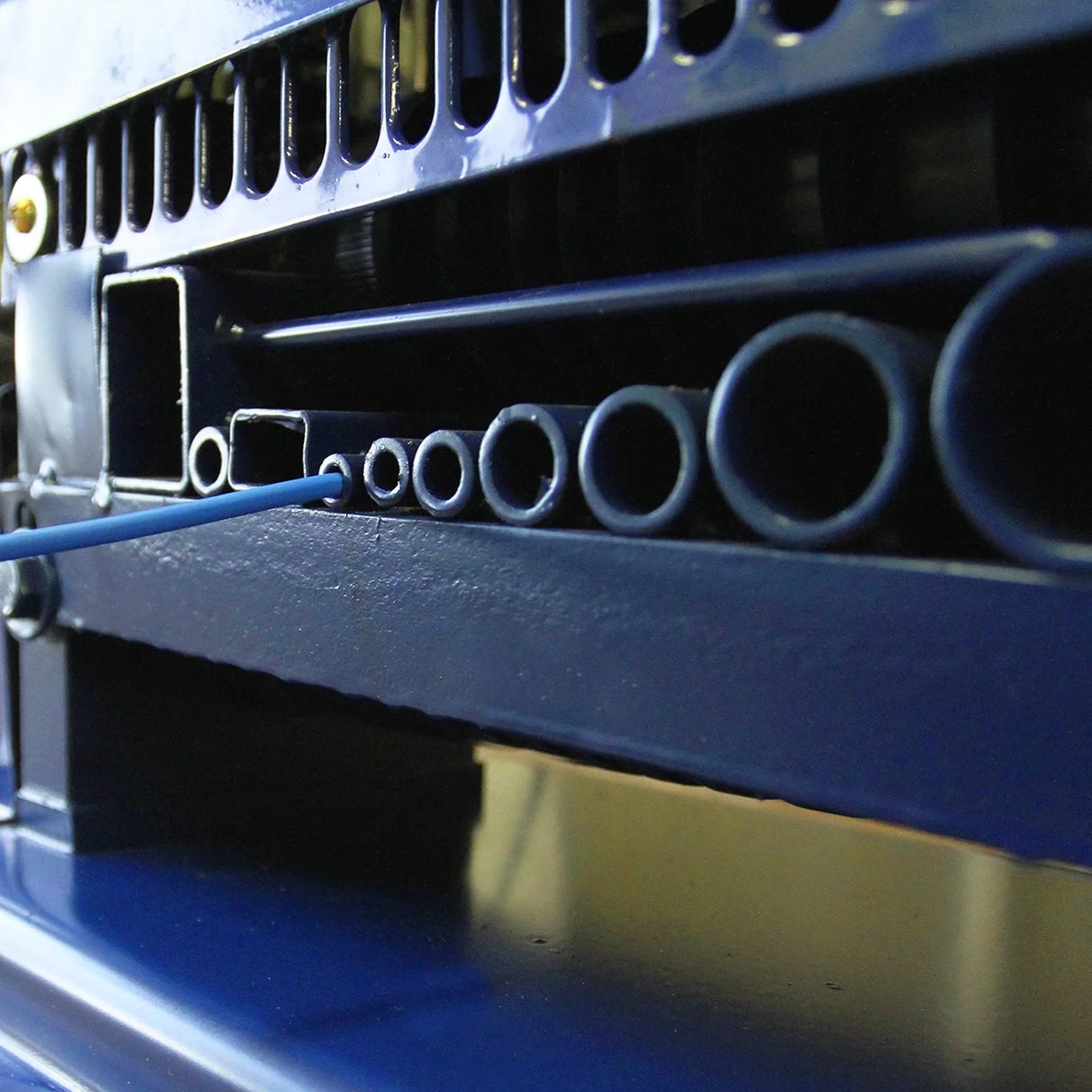 Close-up of the T-Mech Automatic Wire Stripper, showcasing its blue metal body, precision grooves, and various wire gauge slots for efficient stripping