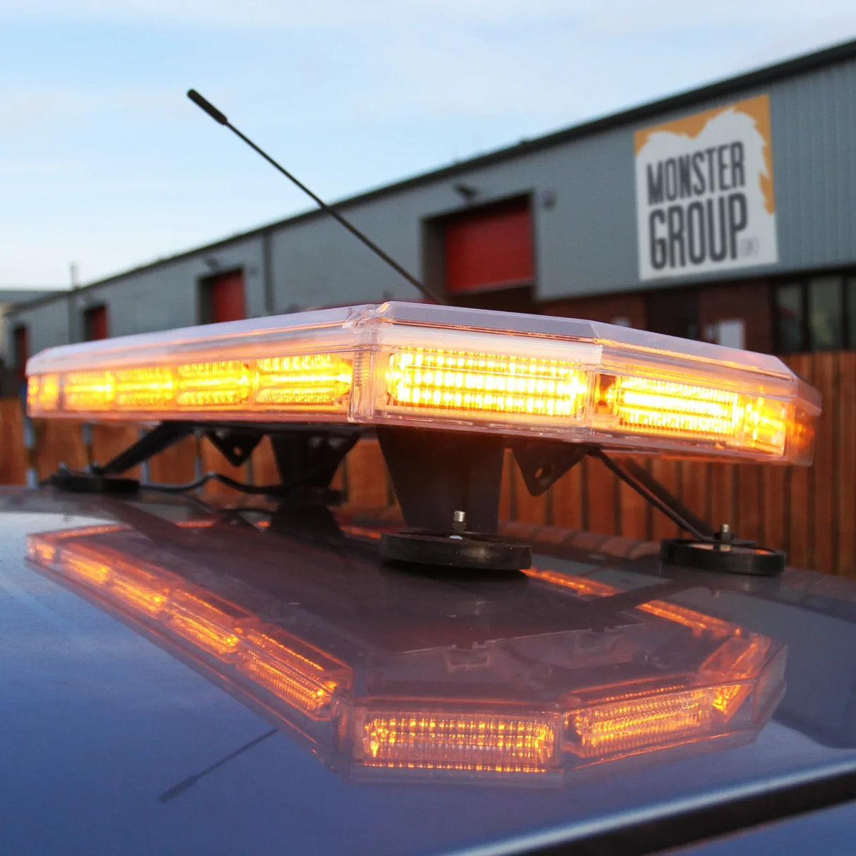 Amber Recovery Light 600mm with bright orange LEDs, mounted on a vehicle roof, reflecting light against a building backdrop