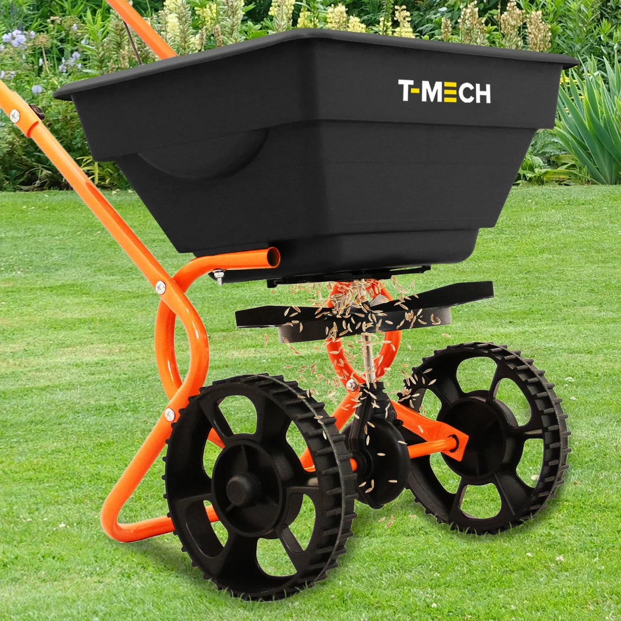 T-Mech Rotary Spreader with a black hopper and orange frame, featuring large wheels and a rotating spreader plate, on green grass