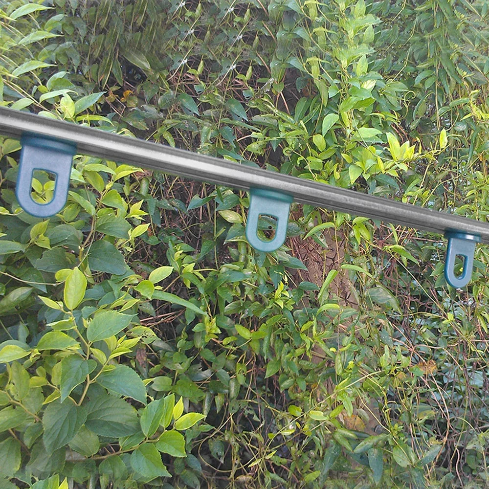 Metal support rail with blue clips for securing plants, surrounded by lush green foliage, designed for the 6ft x 4ft greenhouse