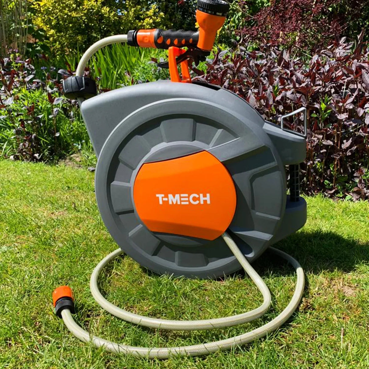 20m retractable hosepipe in gray and orange, featuring a sturdy reel, ergonomic handle, and attached spray nozzle, set on green grass