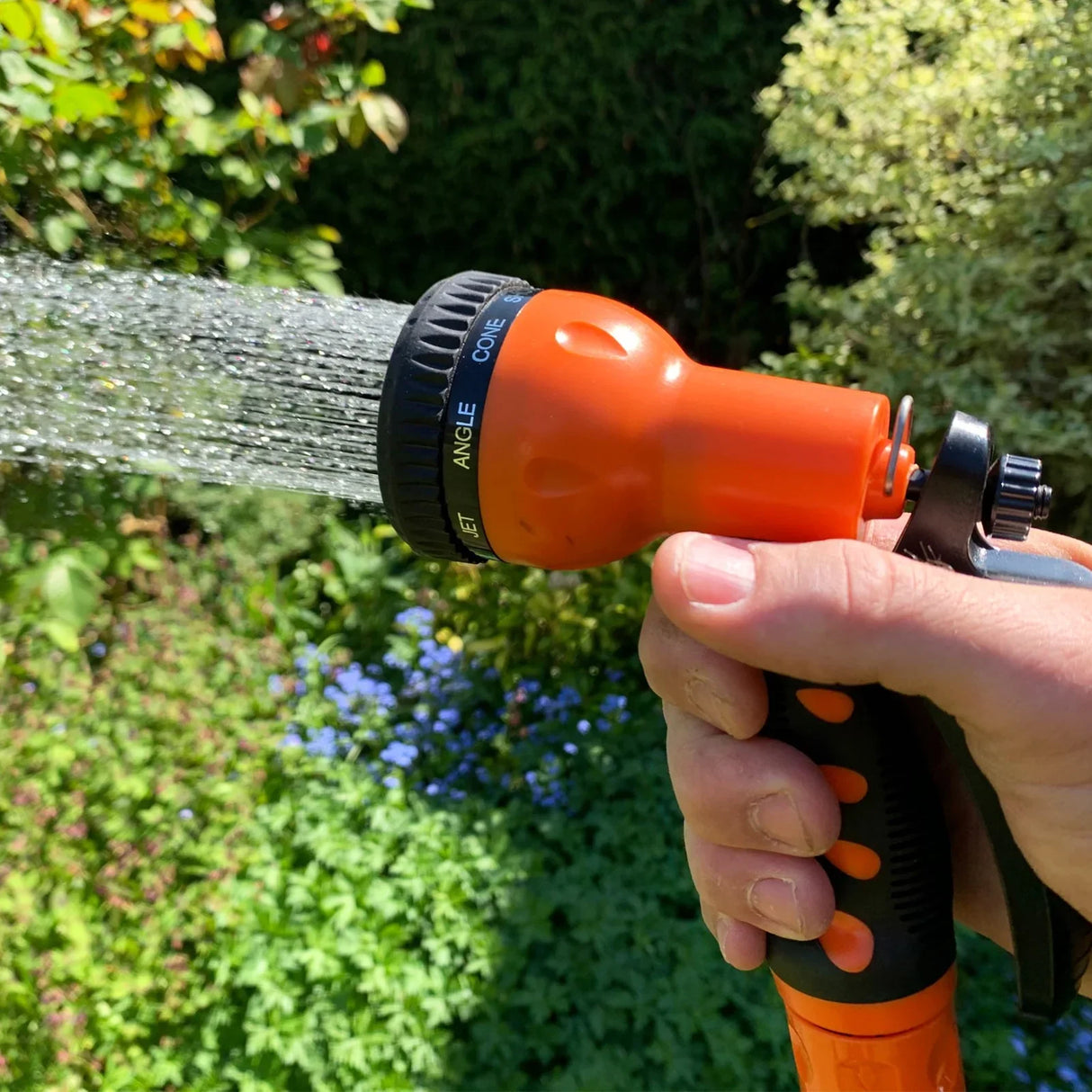 Retractable 20m hosepipe with an orange spray nozzle, featuring adjustable settings, in a lush garden setting with greenery