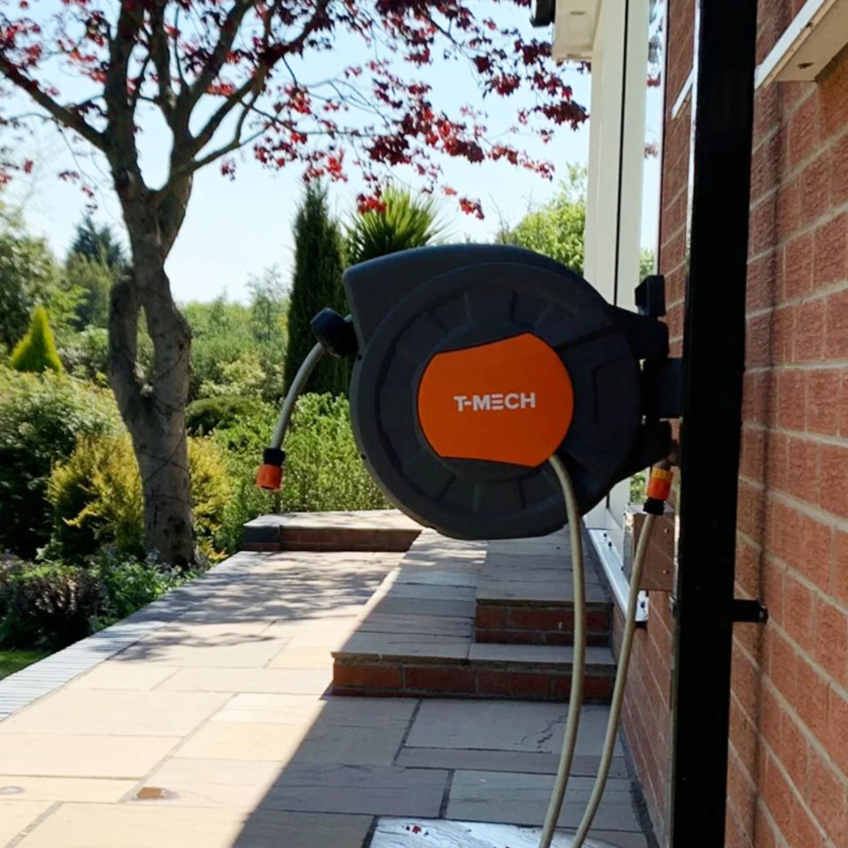 20m retractable hosepipe mounted on a wall, featuring a black and orange design, with a smooth, durable hose ready for use in a garden setting