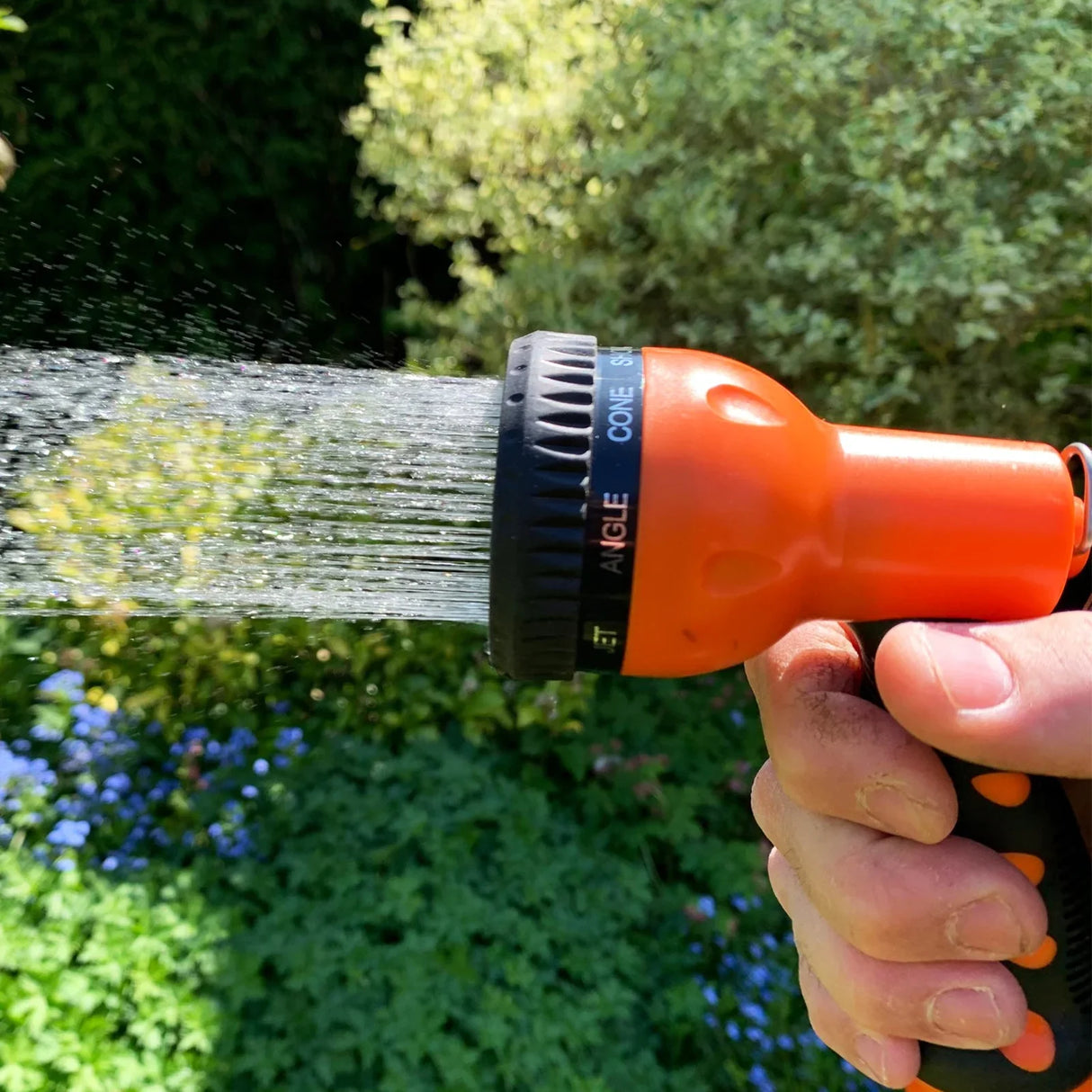 Retractable 30m hosepipe nozzle in hand, featuring an orange and black design with adjustable spray settings for versatile watering