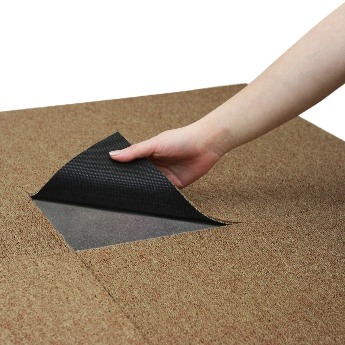 Hand lifting a corner of a sand-colored carpet tile, showcasing its textured surface and durable backing, ideal for flooring
