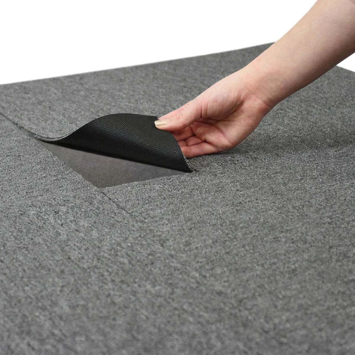 Anthracite grey carpet tile being lifted to reveal its textured backing, showcasing its durable material and easy installation