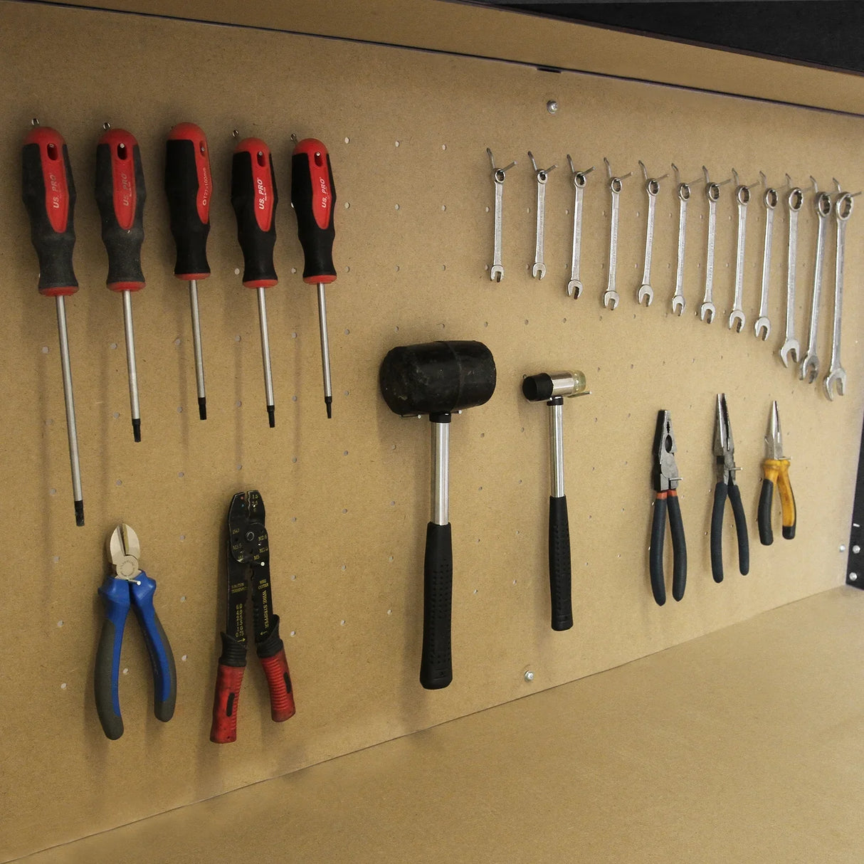 Workbench with black pegboard displaying various tools including screwdrivers, pliers, and hammers for organized storage