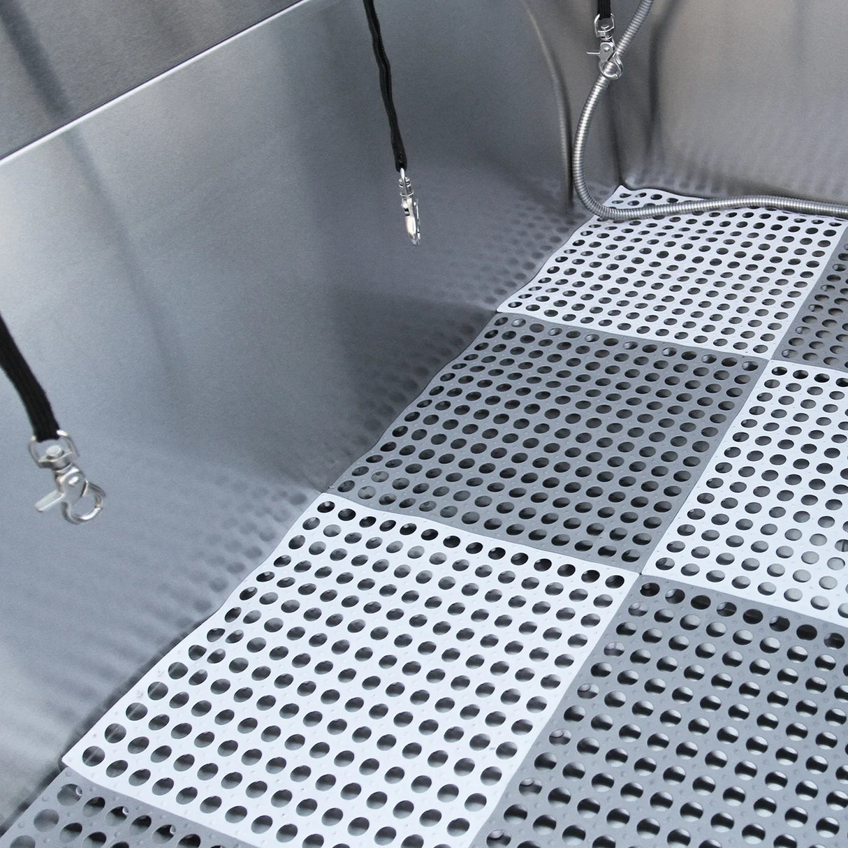Stainless steel dog grooming bath station with a textured, non-slip floor and adjustable shower attachments for easy pet washing