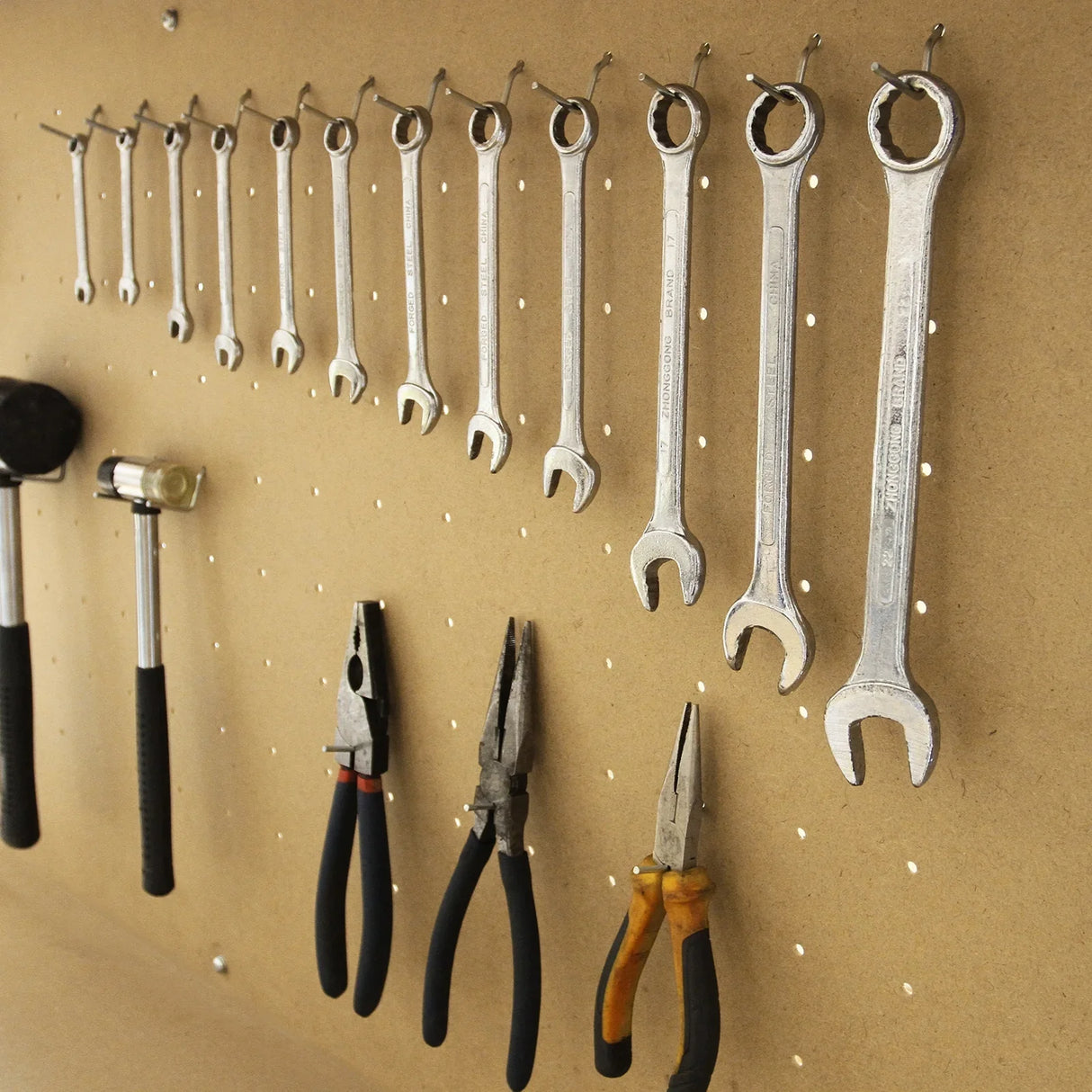 Workbench in blue featuring a pegboard with various metal tools, including wrenches, pliers, and a hammer, organized neatly