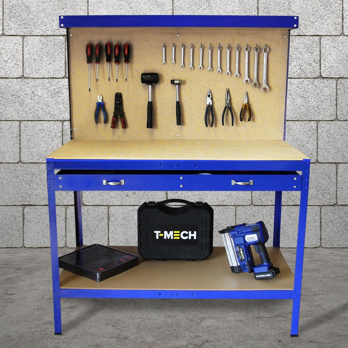 Blue workbench featuring a pegboard with tools, a drawer, and storage for a toolbox and nail gun, set against a concrete wall
