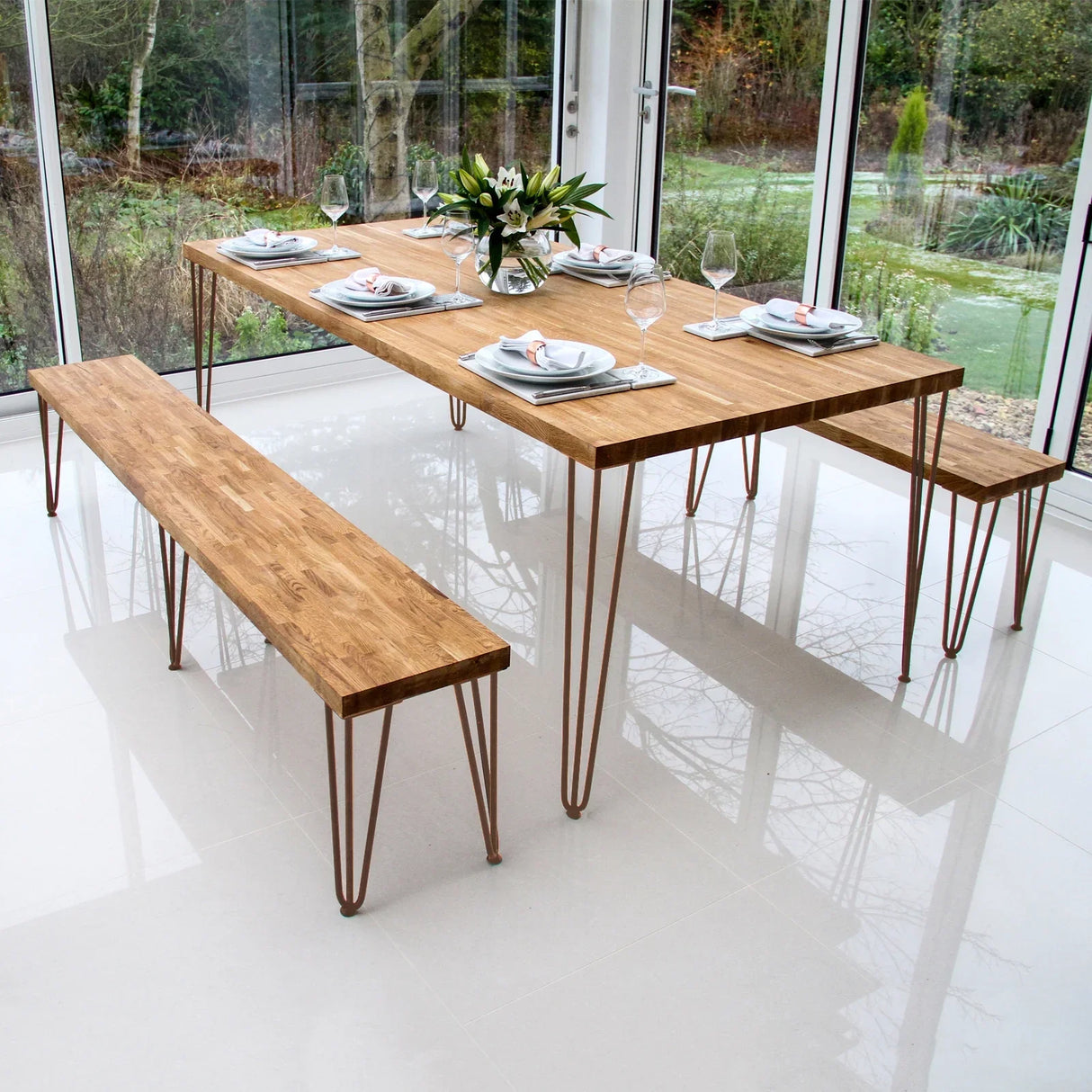 Antique copper hairpin legs, 28 inches tall, support a modern wooden dining table and bench in a bright, contemporary setting