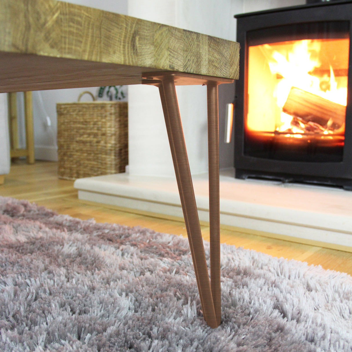 Antique copper 28-inch hairpin legs with a sleek 2-prong design, supporting a wooden tabletop near a cozy fireplace on a soft rug