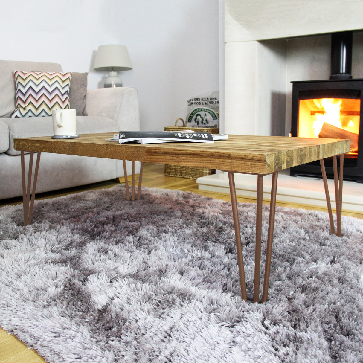 Antique copper hairpin legs, 28 inches tall, with a sleek 2-prong design, supporting a wooden coffee table in a cozy living room setting