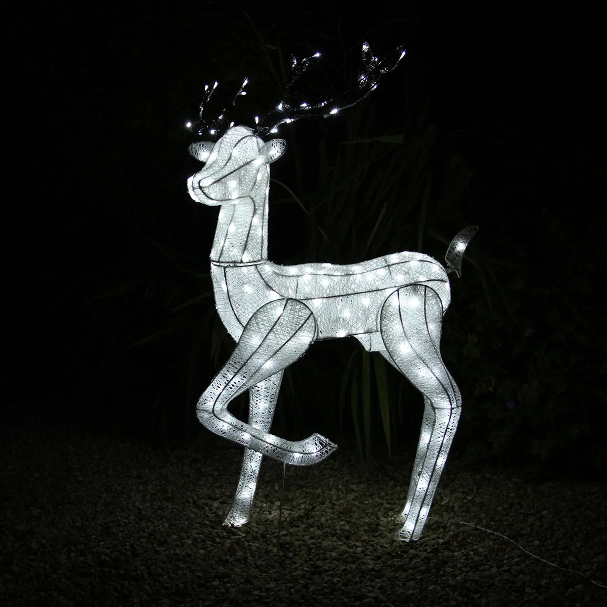 Large light-up stag reindeer with glowing white LED lights, standing gracefully among dark foliage, perfect for festive outdoor decor